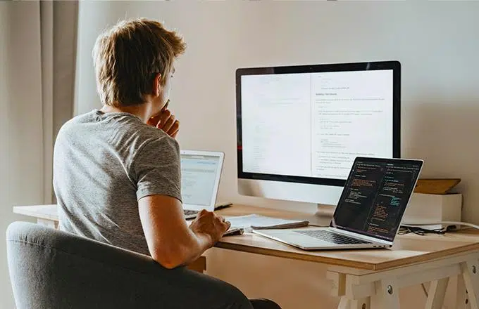 person sat at desk in front of laptop and monitor