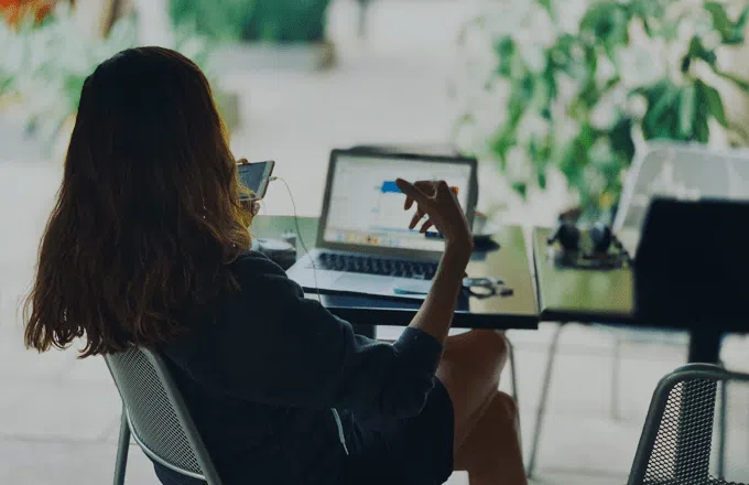 person sat at desk with laptop talking on mobile phone