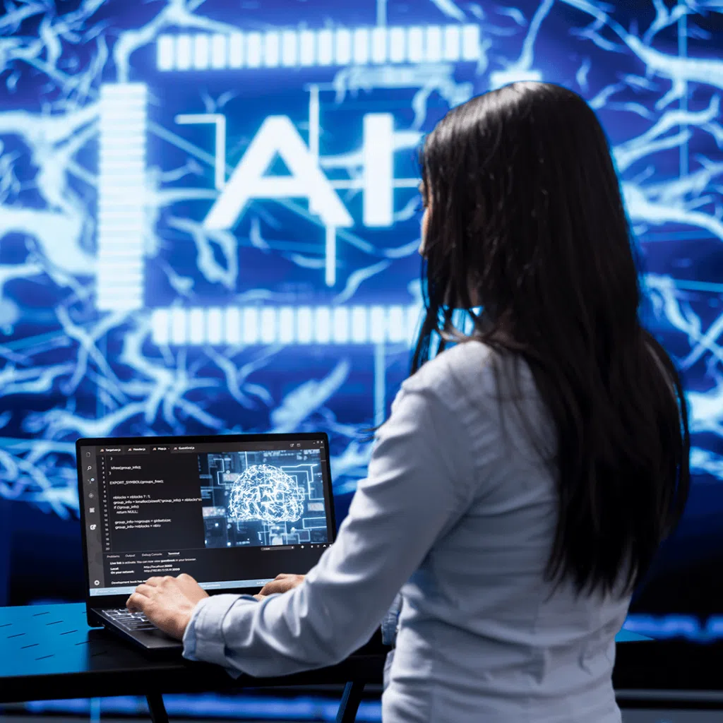 A woman with long dark hair works on a laptop in front of a large digital display featuring the letters “AI” and a glowing, electric-style blue background. The screen on her laptop shows code and an abstract neural network graphic.