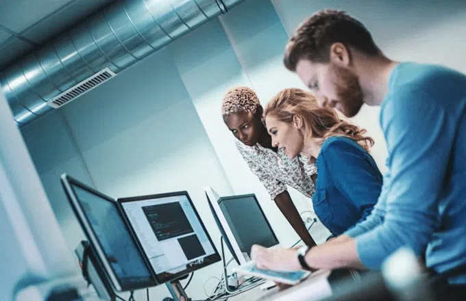 3 people in a modern office working at their computers