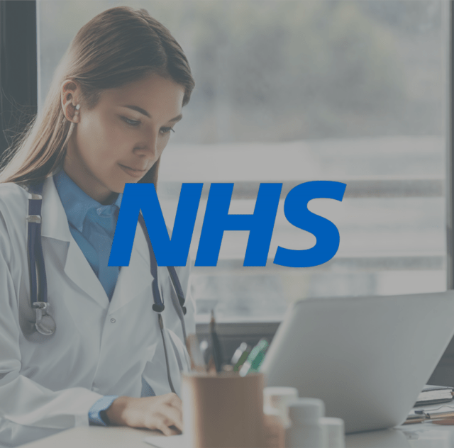 doctor sat at desk with laptop with NHS logo overlaid