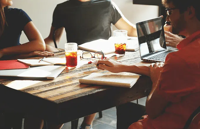 people sat at table with books and laptops