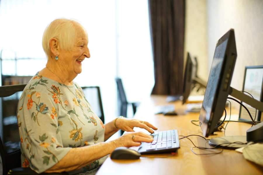 An elderly woman typing at a computer