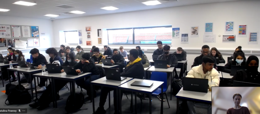 A zoom call showing young people working on laptops in classroom