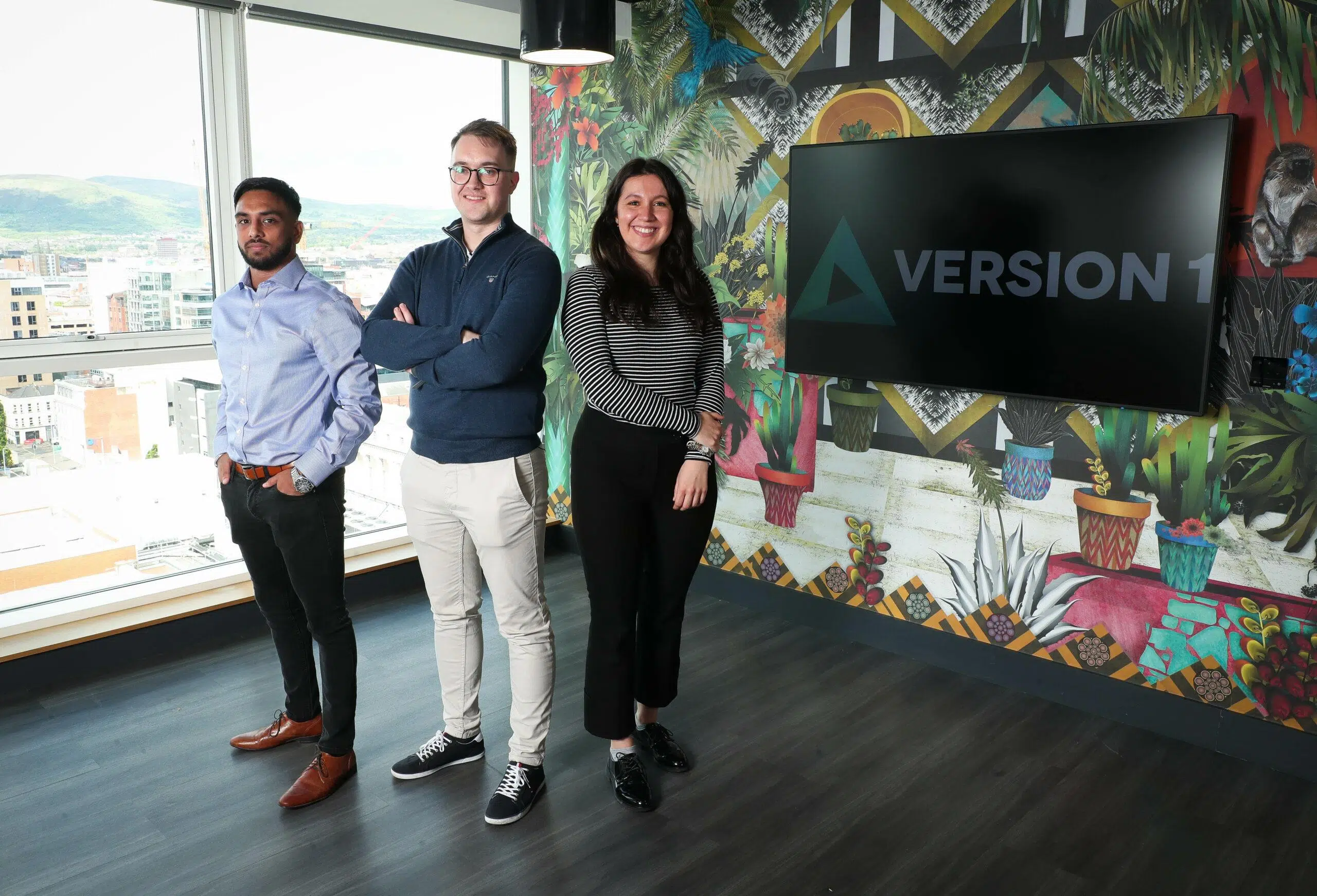 3 people in a modern office with Version 1 on screen behind them