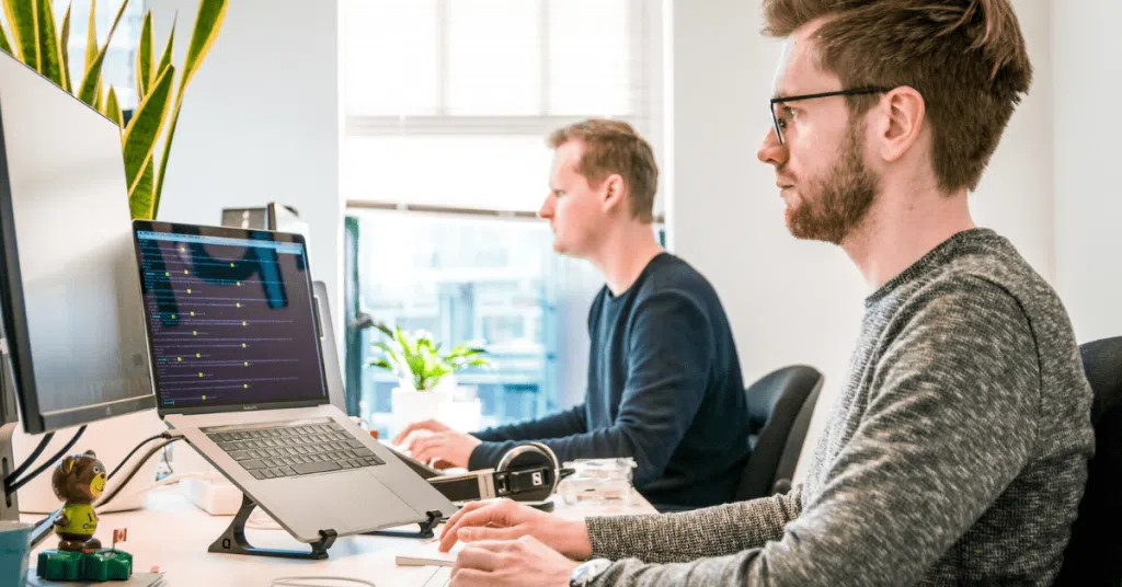 people at desk with laptop and monitor