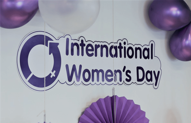 International Womens Day - picture of a wall decorated with a poster and balloons