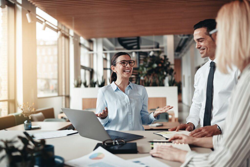 Three people smiling and talking at a desk