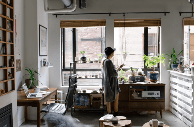 woman in trendy hipster home working space wearing a hat, using a tablet