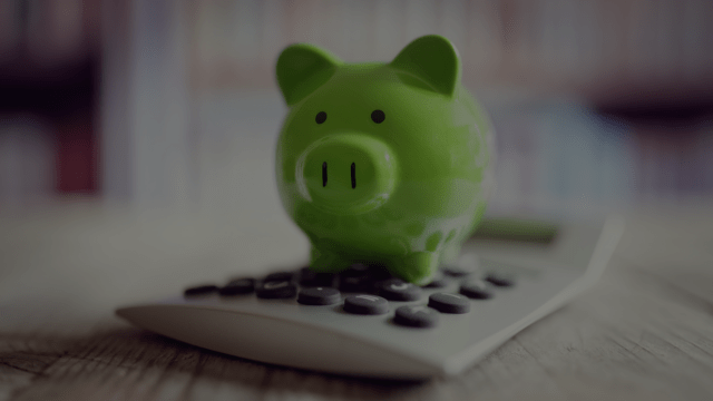 green piggy bank stood on a calculator