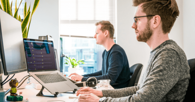 people at desk with laptop and monitor