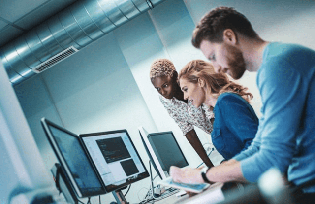 3 people in a modern office working at their computers