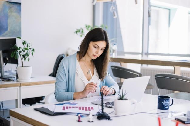 Woman at desk with laptop and printouts