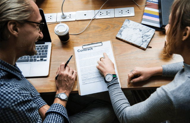 Birds of view of two people reading a contract at a desk