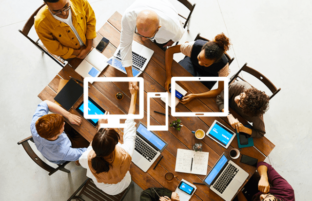 Group of people working at a table on laptops