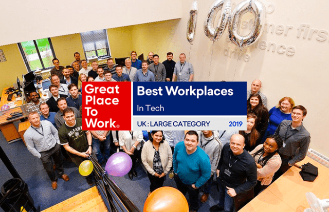 Great Place to Work poster laid over a photo of a large group of people smiling with balloons in an office