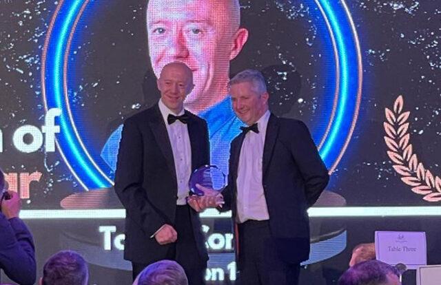 Two men holding an award at an event