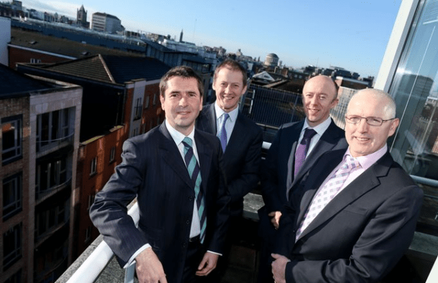 4 men in suits on a balcony