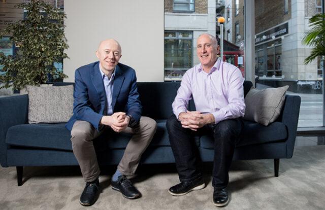 Two men sat on a sofa in an office