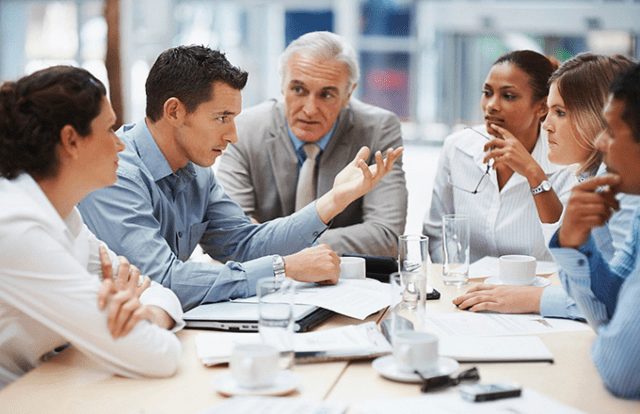 people in a meeting sat at a table talking