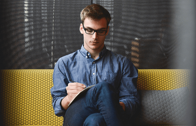 man sat writing in notebook
