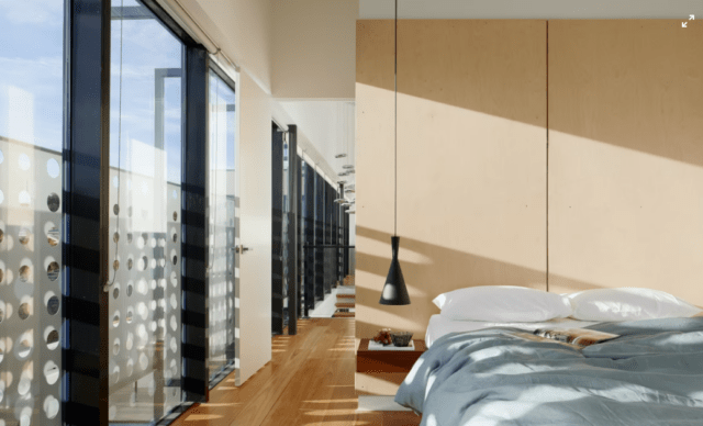 A capture of a modern furnished bedroom with big floor to ceiling windows.