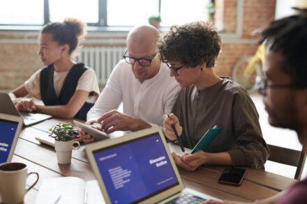 People around a table using laptops and tablets