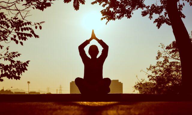 Silhouette of a person doing yoga outside