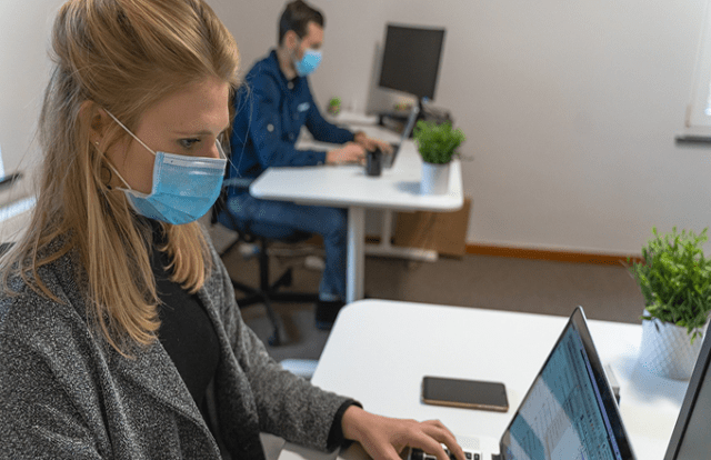 person at desk in office wearing face mask
