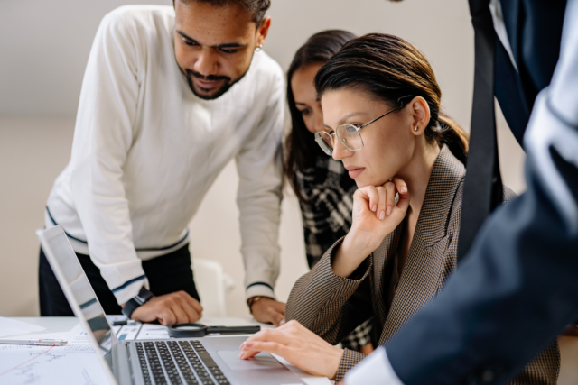 Three people looking at a laptop