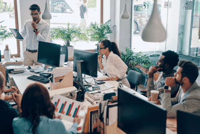group of professionals working in a bright office around computers