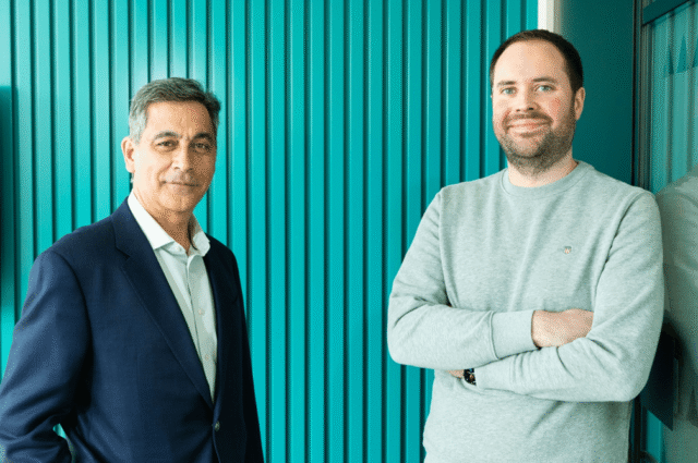 Two business leaders stand side by side against a teal backdrop, representing Version 1’s announcement of Sarita Sudera as Chief Commercial Officer and David Churchill as Chief People Officer.