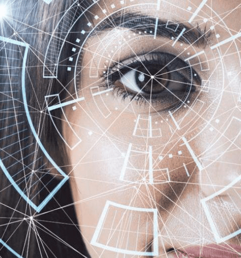Close-up of a human eye partially framed by dark hair, overlaid with a network of geometric lines, circular grids, and digital interface elements resembling a futuristic or biometric scanning display. The design includes concentric circles centered on the eye and angular shapes in light blue and white tones, suggesting themes of technology, data analysis, or artificial intelligence. The background is softly blurred, keeping focus on the eye and the transparent graphical overlay.