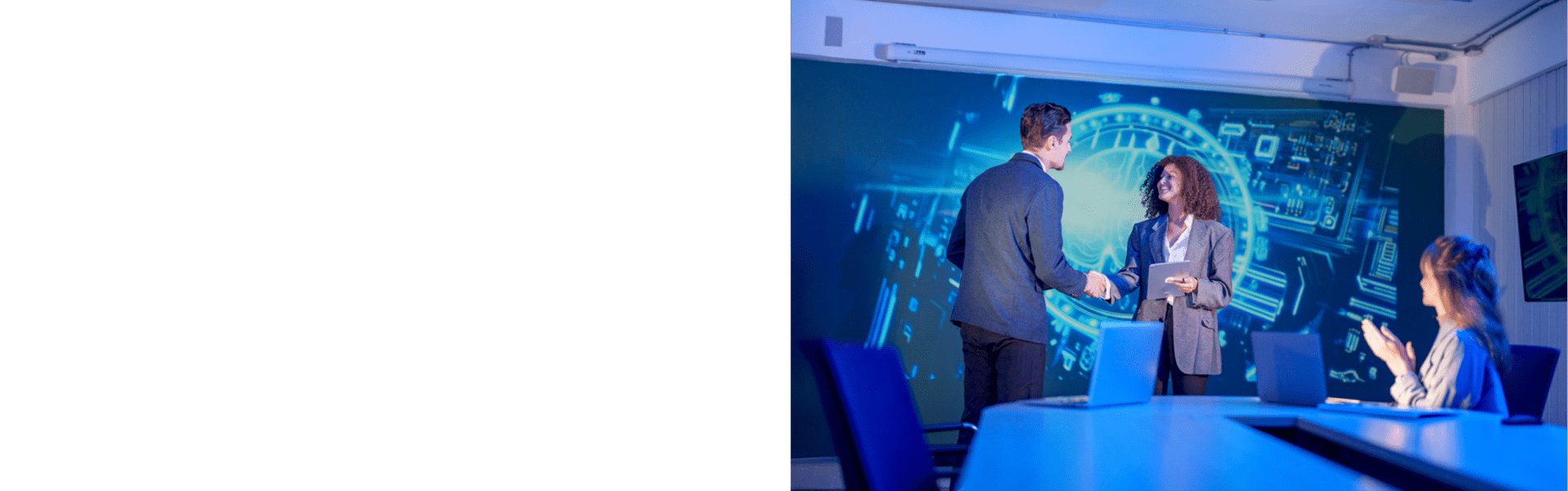 Two professionals shake hands across a conference room table in front of a large digital display showing AI and technology graphics. Laptops sit on the table, while another attendee applauds from the side. The image illustrates business collaboration and enterprise AI partnerships, including technologies and platforms such as Claude by Anthropic within the broader artificial intelligence ecosystem.