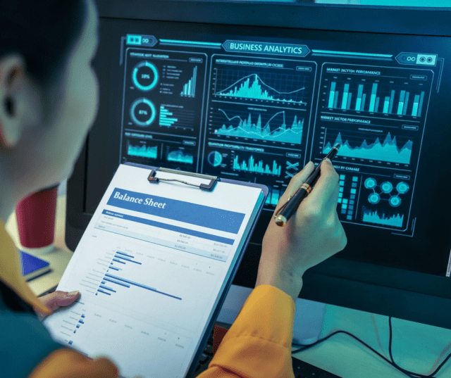 An Asian businesswoman analyzes digital charts on a computer screen, reviewing performance reports