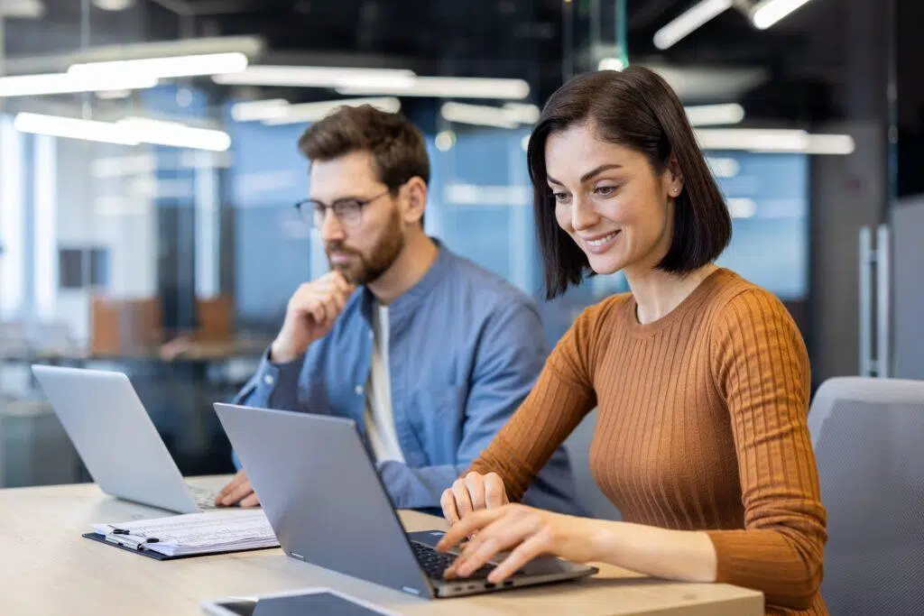 Man and Woman each looking at their laptops