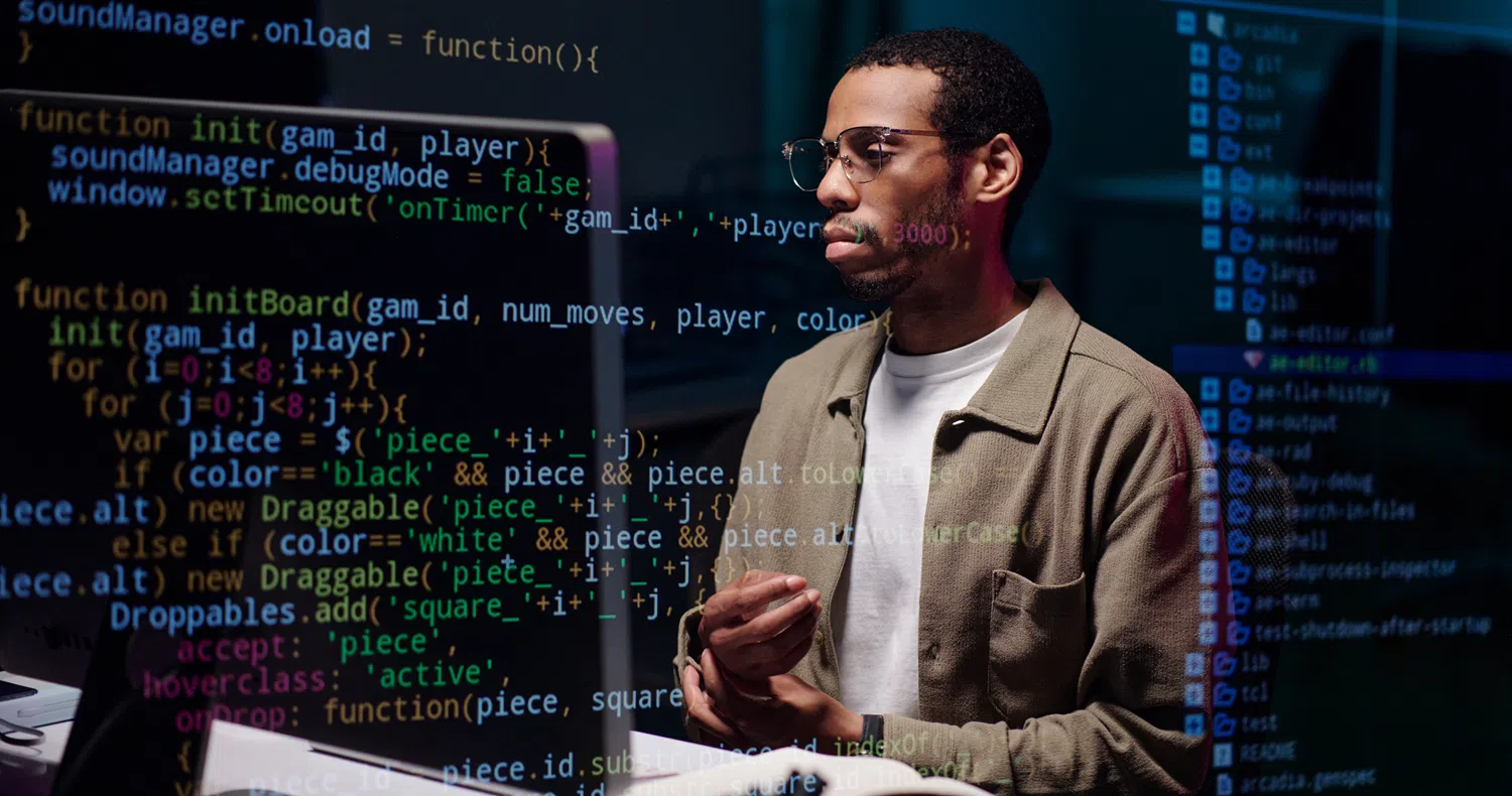 Person working at a computer with lines of programming code overlaid on the screen, illustrating software development, coding, data engineering, or AI technology.